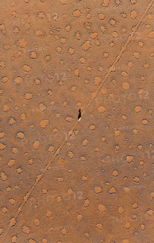 A vehicle of the balloon ground crew crosses a sandy plain with so-called Fairy Circles at the edge of the Namib Desert