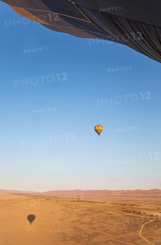 Hot-air balloon above a sandy plain at the edge of the Namib Desert