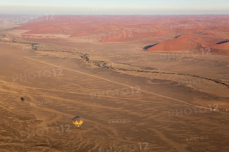 Hot-air balloon above an arid plain and the dry riverbed of the Tsauchab river at the edge of the Namib Desert