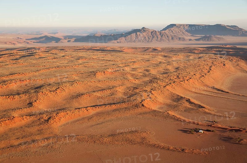 Farmhouse at the foot of a large grass-grown dune at the edge of the Namib Desert