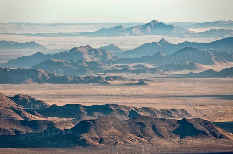 Isolated mountain ridges at edge of Namib Desert with coastal fog behind