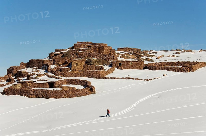 Snow covered Berber village and skier near to the Oukaimeden skiing centre in the High Atlas mountains