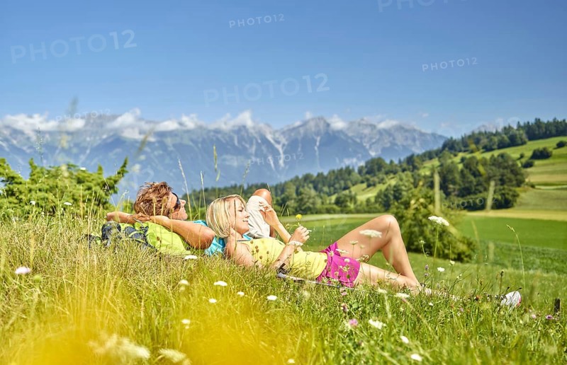 Man and woman lying in a flower meadow with a view of the North Chain