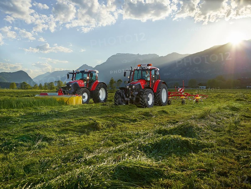 Two tractors mowing and tedding the cut hay