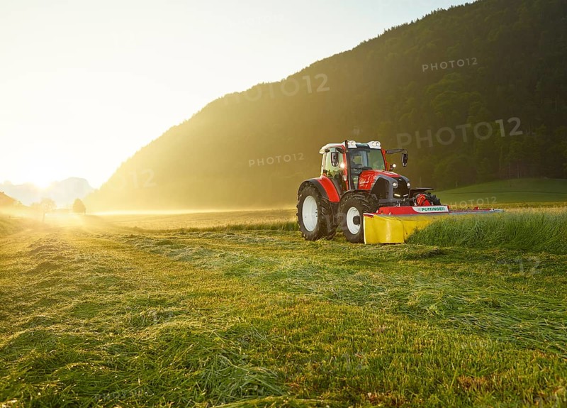 Tractor mowing a field at sunrise
