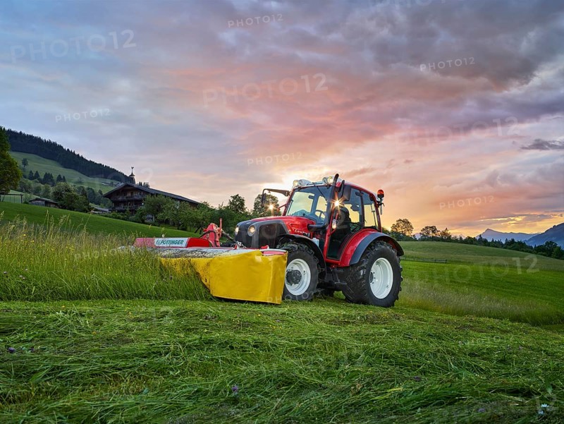 Tractor mowing a field at sunrise