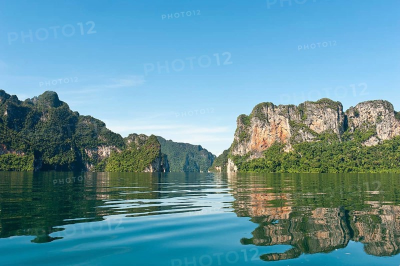 Forested karst limestone mountains reflected in the water