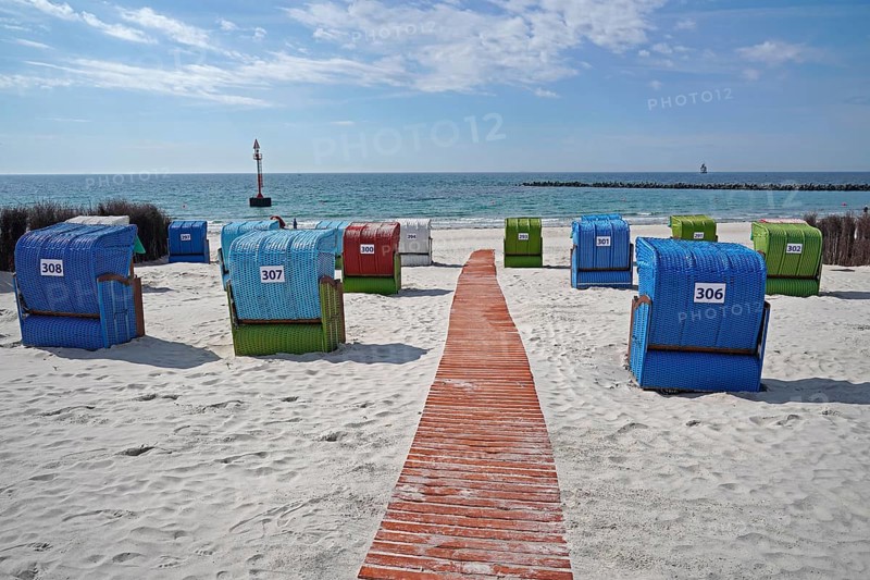 Wooden walkway between colourful beach chairs