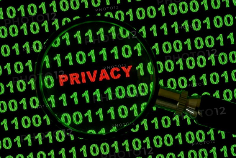 Binary code with the word 'Privacy' viewed through a magnifying glass