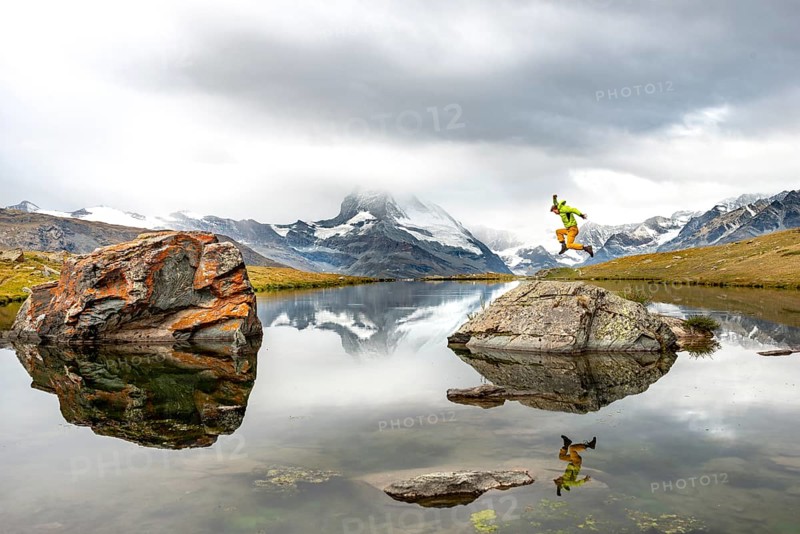 Hiker jumps on rocks in the lake