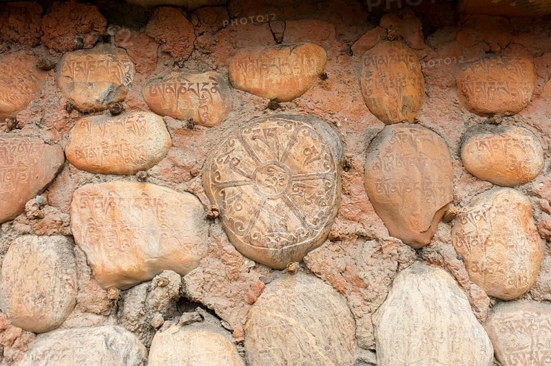 Mani stones with Tibetan inscriptions on wall