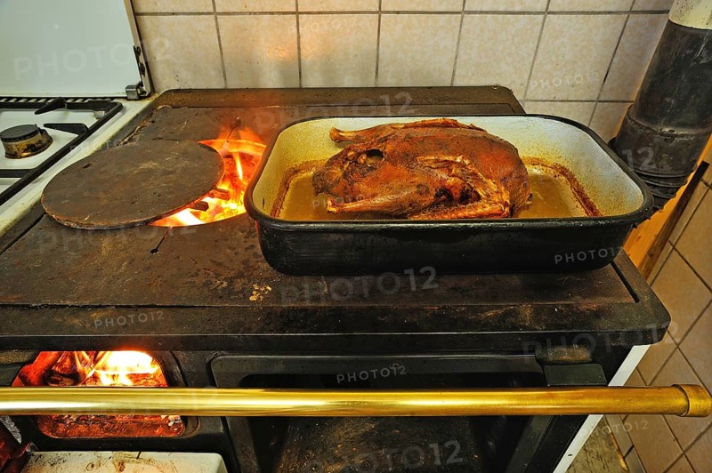 Ready roast duck in a roasting pan on an old coal-fired stove with open fire plate