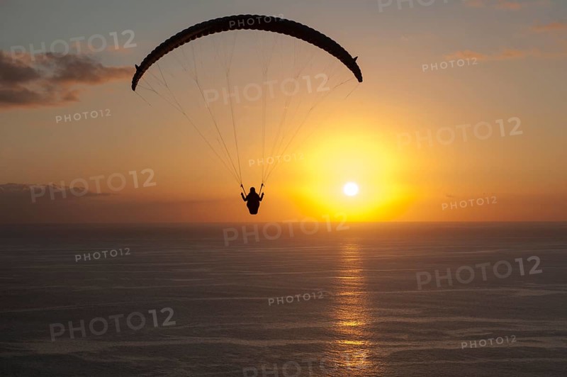 Paraglider over the Atlantic Ocean with sunset