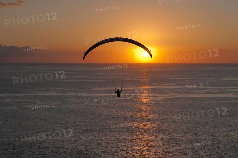 Paraglider over the Atlantic Ocean with sunset