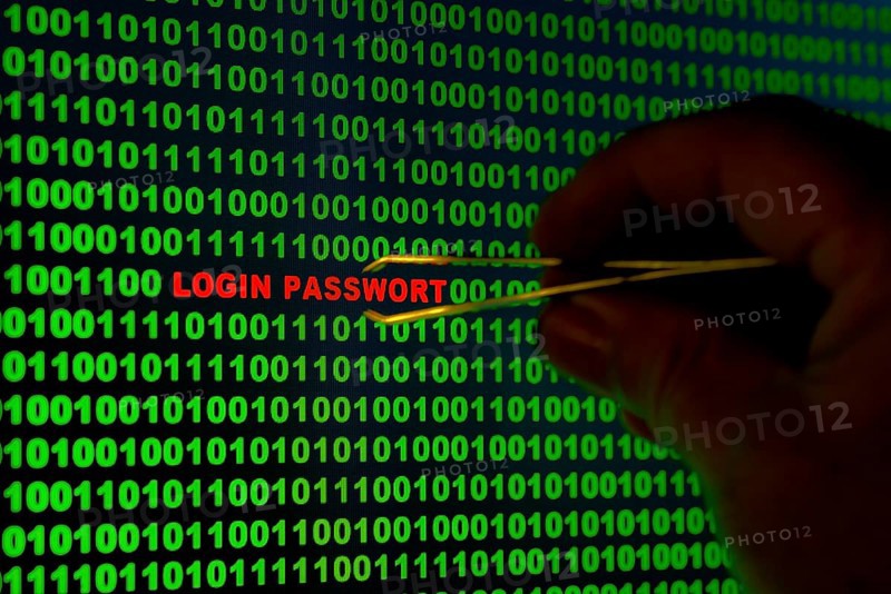 Hand reaching for the words 'Login Passwort' with tweezers in a binary code
