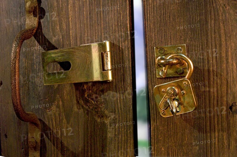 Old wooden door with metal fittings and an open padlock
