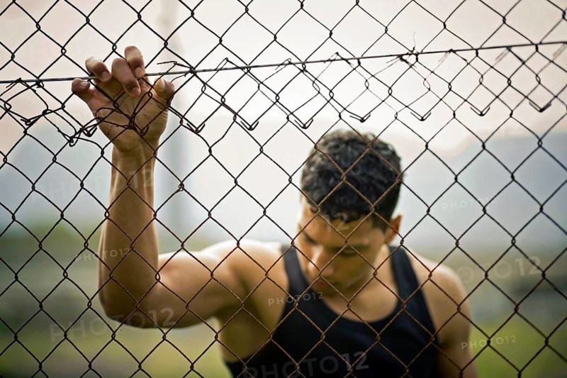 Young man holding onto a fence