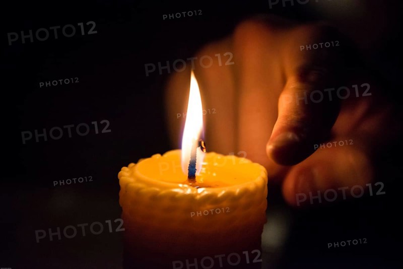 Finger next to a burning wax candle
