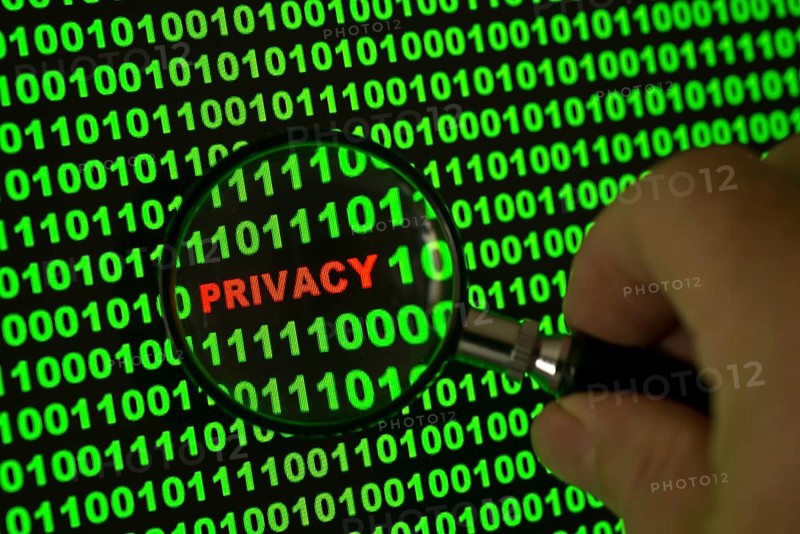 Binary code with the word 'Privacy' viewed through a magnifying glass