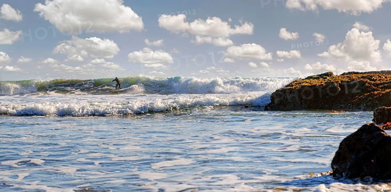 Surfer in the surf on the Pacific beach near Cambria