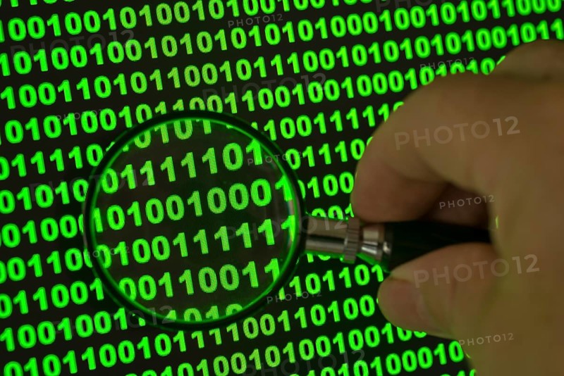 Binary code viewed through a magnifying glass
