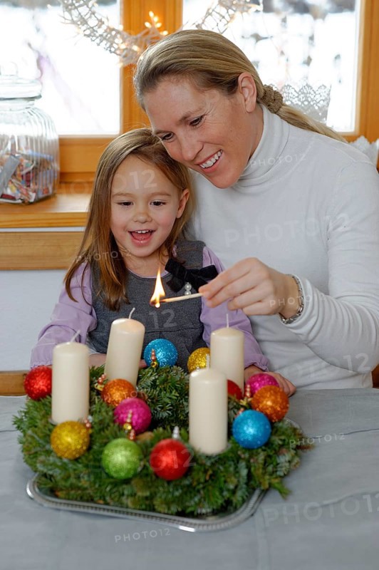 Mother and daughter lighting the first candle on the Advent wreath