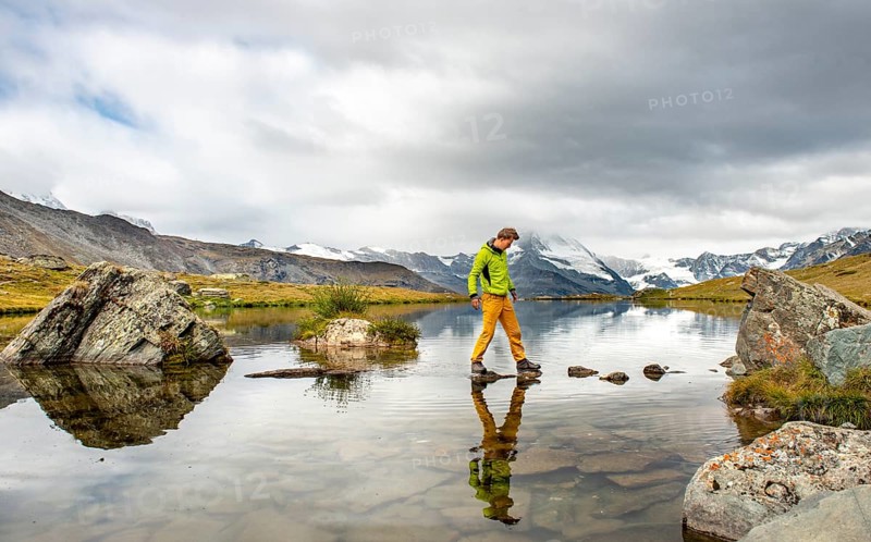 Hiker walks over stones in the water