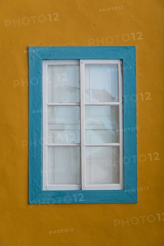 Turquoise coloured window with a yellow facade