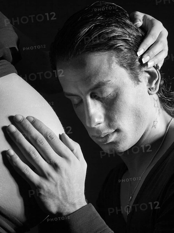 Man putting his hand on the belly of a very pregnant woman