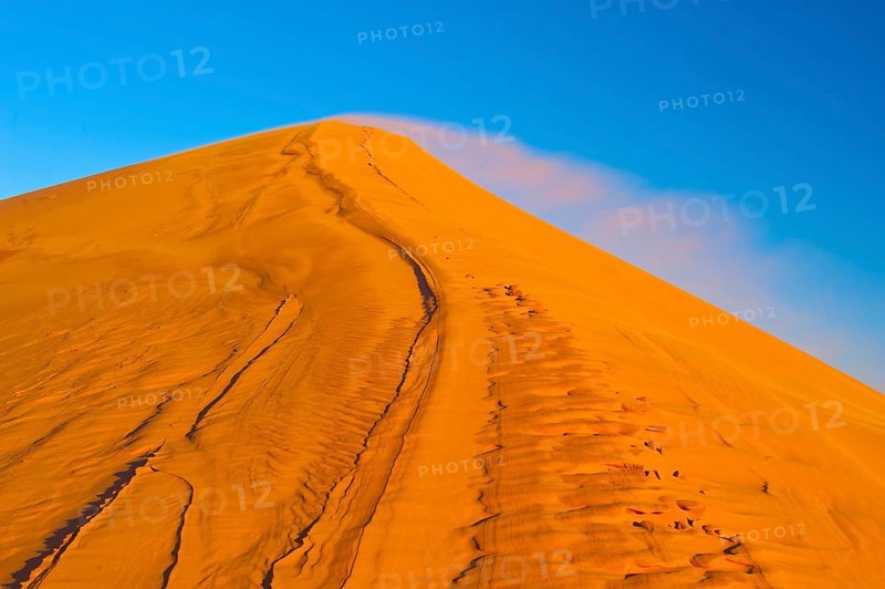 Wind blowing fine sand over the crest of a sand dune