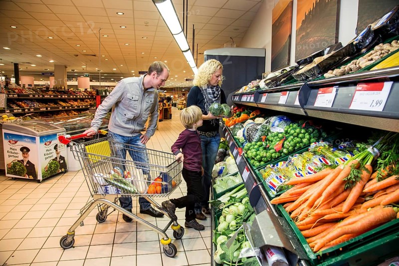 Family shopping with a shopping trolley in the fruit and vegetables department of a supermarket