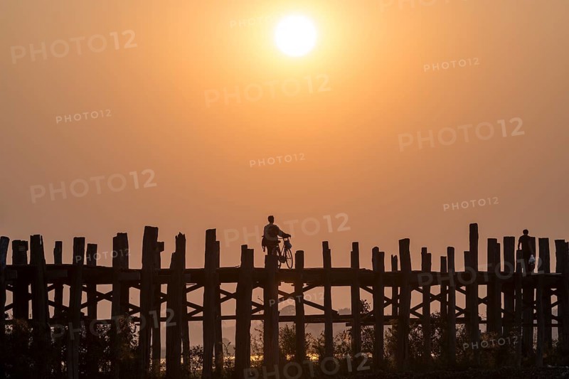Man riding a bike on a teak bridge