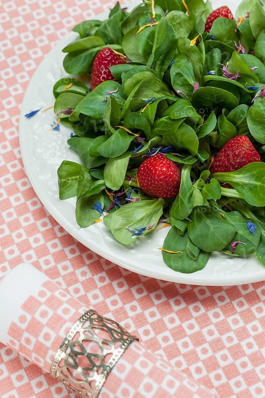 Cornsalad with strawberries and petals served on a plate