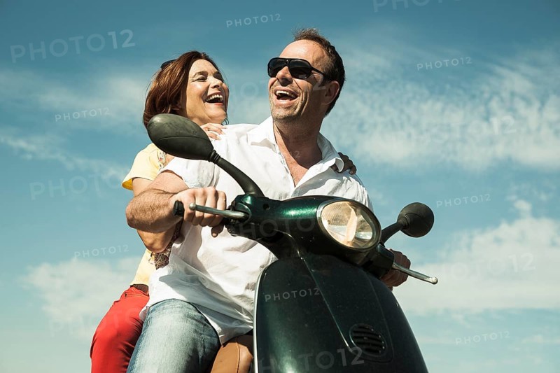 Smiling couple driving with the scooter