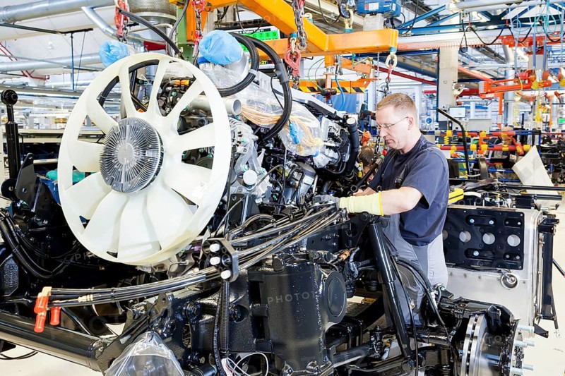 Employee installing the engine and transmission in a chassis at MAN Truck and Bus AG