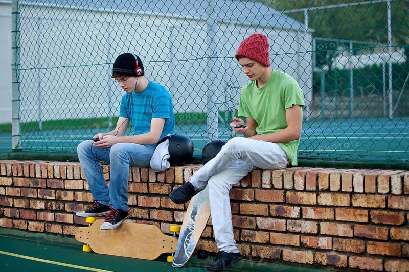 Two teenage boys sitting on a brick wall