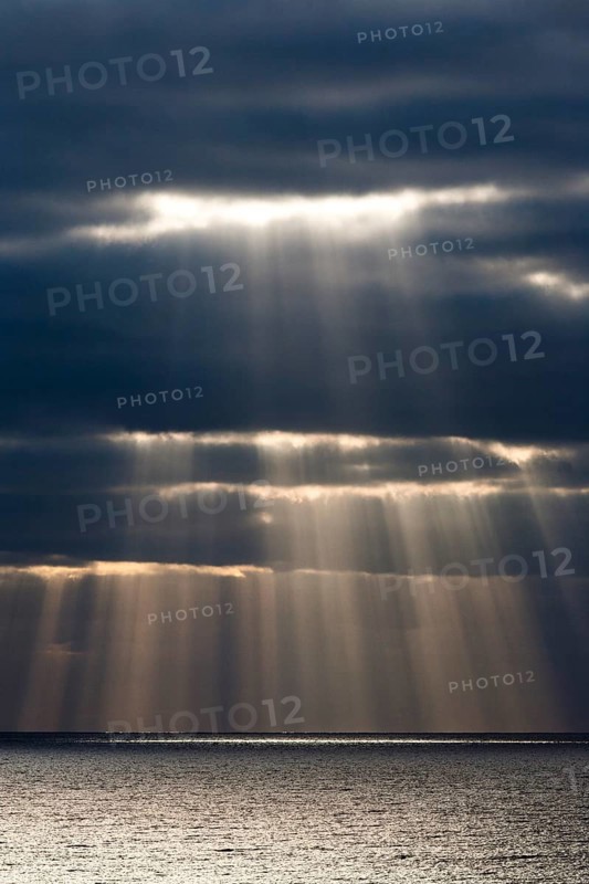 Sun rays shine through dark storm clouds