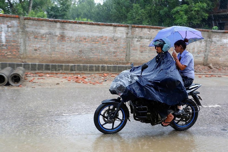People on motorcycle on flooded road after monsoon storm