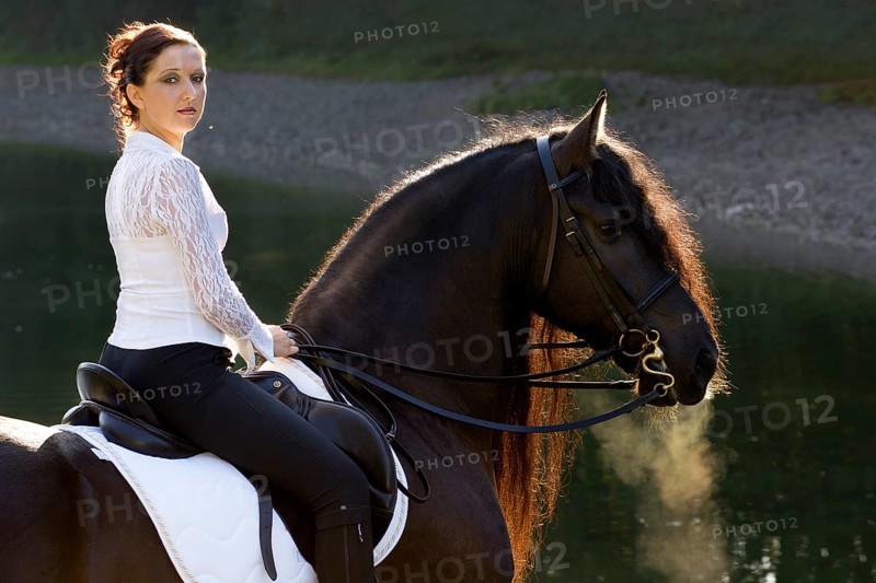 Horsewoman riding a black Friesian horse