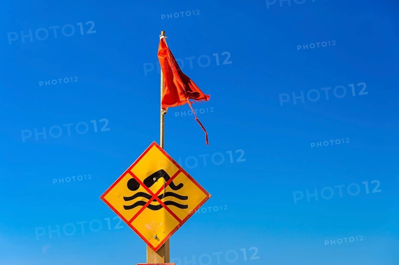 Bathing prohibition sign with red flag in front of a blue sky