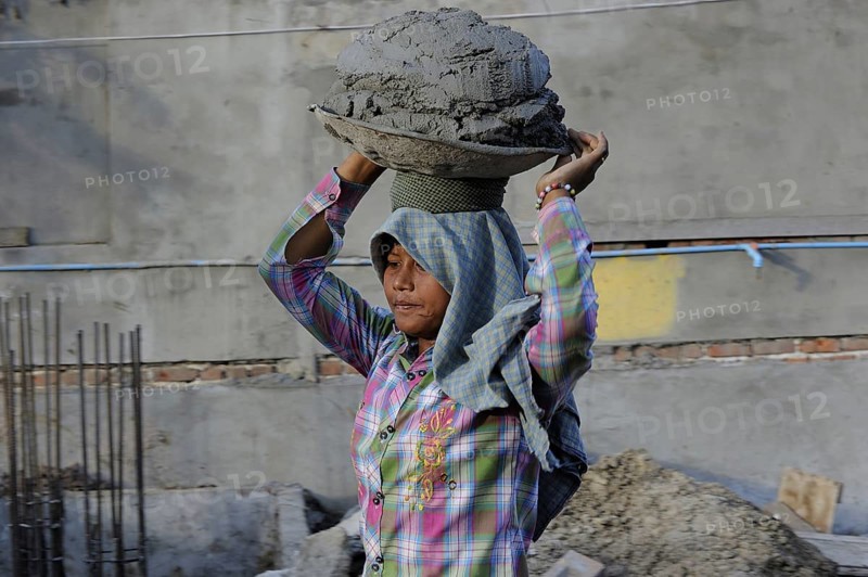 Female construction worker carrying concrete on her head