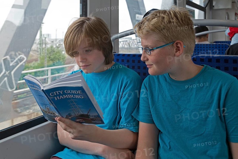 Young people on a language trip read an English travel guide on the train