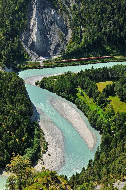 Train of the Rhaetian Railway on the riverbanks of the Vorderrhein