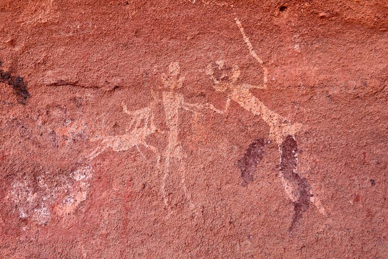 Rock painting of people with dogs