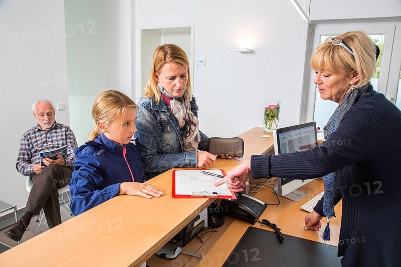 Patients filling in a form at the reception of a dental office