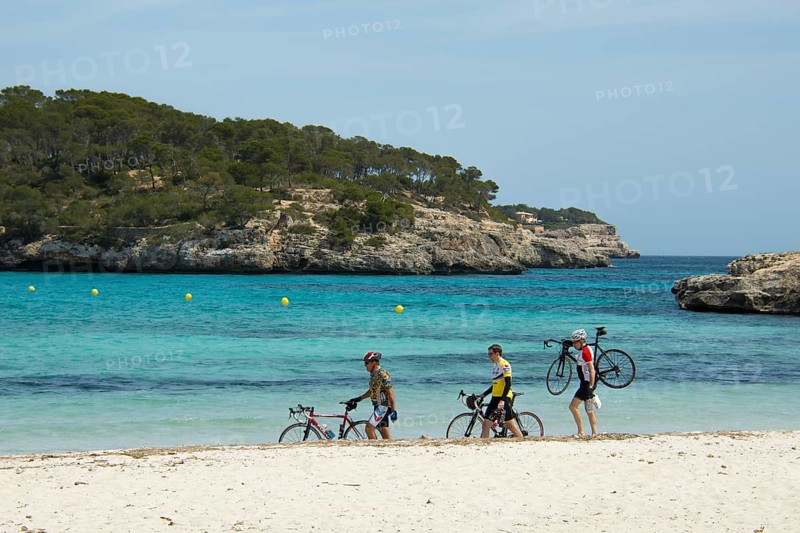 Racing cyclists walking along the beach