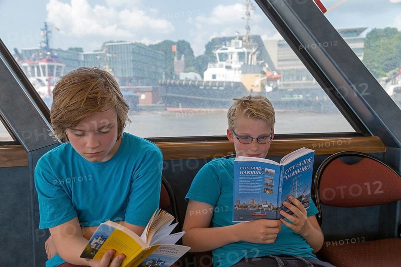 Young people on a language trip read an English travel guide on the Elbe ferry