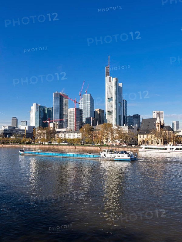 Cargo ship on the Main river in front of the skyline of Frankfurt with the buildings of Opernturm