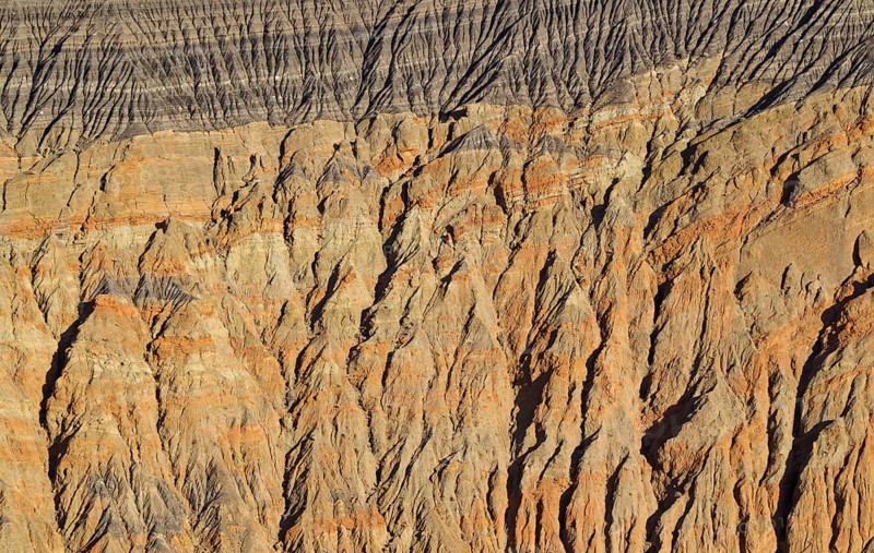Exposed fissured bedrock of orange-colored conglomerate on the crater wall of Ubehebe Crater