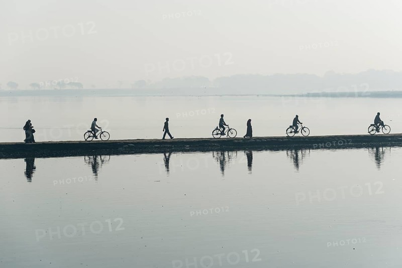 Cyclists and pedestrians crossing the Yamuna river on a dam in the morning
